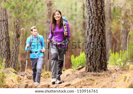 Hikers in forest. Couple hiking in fall forest. Asian woman hiker in front smiling happy. Photo from Aguamansa, Orotava, Tenerife, Canary Islands, Spain.