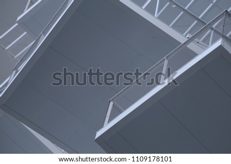 Close up outdoor view of pattern of white rectangular balconies seen from bellow. Abstract urban image with polygone shapes, angles and lines. Modern architecture with ceilings and exterior barriers. 