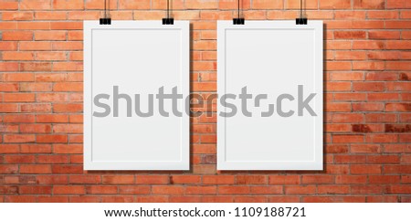 
White poster Or a white frame hanging on the brick wall background in the room.