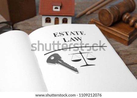 House key and book with words ESTATE LAW on table, closeup