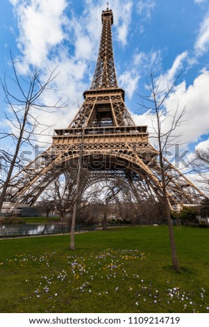 Wide angle view of iconic Eiffel tower with dramatic cloudy blue sky in the background. 