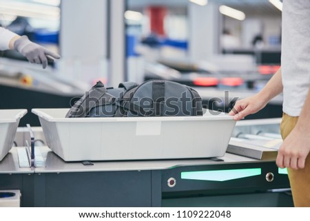Airport security check. Young man (traveler) waiting for x-ray control his luggage. Royalty-Free Stock Photo #1109222048