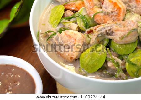 Boiled fresh Bamboo shoot with shrimp and Sator (Thai local vegetable ) in coconut milk, Thai food eat with Spicy Shrimp Paste Dip (Nam Prik Kapi) in white bowl 

