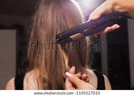 professional hairdresser curling a hair strand of a model with relaxed hair in a beauty salon. concept of stylist training Royalty-Free Stock Photo #1109227010