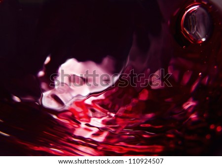 Red wine on a black background, abstract splashing. Royalty-Free Stock Photo #110924507