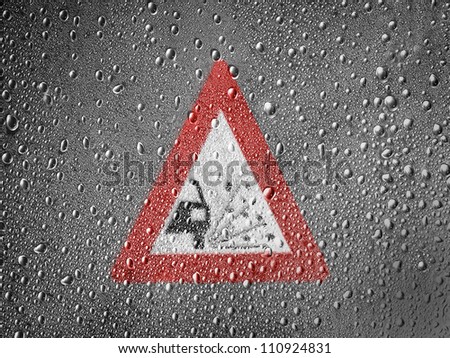 Gravel road sign painted on metal surface covered with rain drops