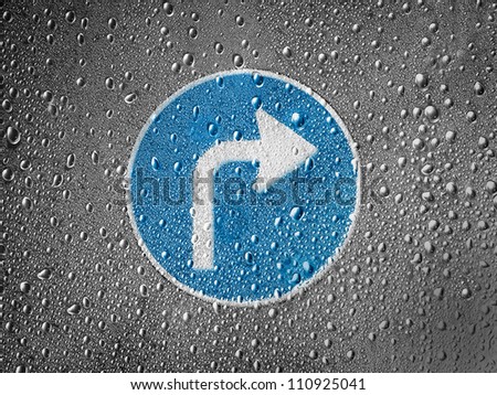 Right turn road sign painted on metal surface covered with rain drops