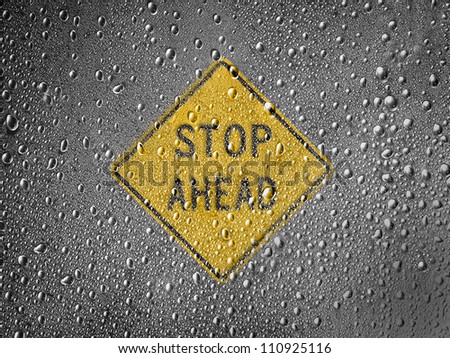 Stop ahead road sign painted on metal surface covered with rain drops