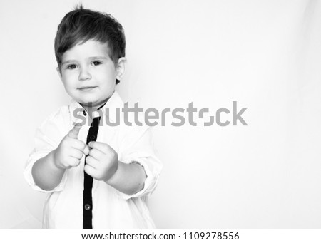 Cheerful and handsome young boy in white shirt looking at camera with smile while standing against white background. Black and white. Free space for text