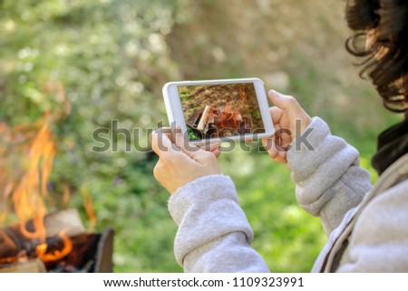 Woman is taking pictures of the fire on her smartphone. Outdoors. Close-up.