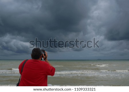 photographer man, takes pictures of the sea on clouds  Rain background.