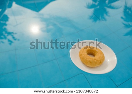 Donut on white plate floating in swimming pool