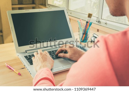 Orange t-shirt businessman typing laptop or notebook in home office vintage. Small business SME or start up businessman concept. Business and 
technology about communication or contact