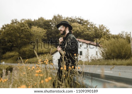 Vintage young man is sitting on guardrails observing the landscape