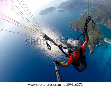 Paragliding in the sky. Paraglider tandem flying over the sea with blue water and mountains in bright sunny day. Aerial view of paraglider and Blue Lagoon in Oludeniz, Turkey. Extreme sport. Landscape Royalty-Free Stock Photo #1109416373