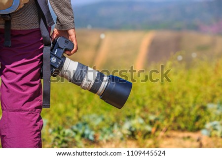 Photographer holds her DSLR camera with telephoto lens in her right hand
