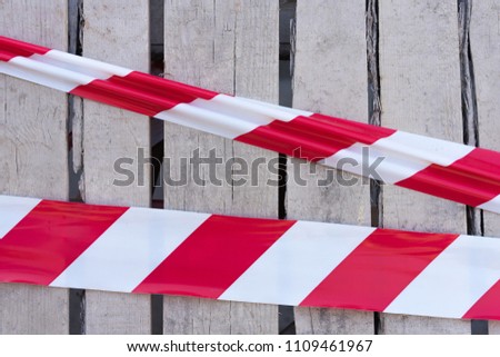 Line of barrier signal red and white tape warning tape used for hazards and awareness set against on the background of a wooden wall