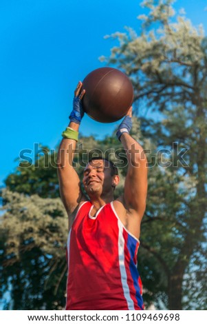 Young athlete performs sports exercises with a ball outdoors