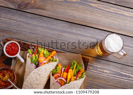 Tortilla with chicken and vegetables and beer to drink. 