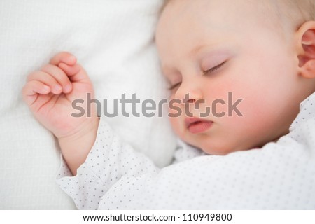 Peaceful baby lying on a bed while sleeping in a bright room Royalty-Free Stock Photo #110949800
