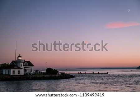 Mukilteo, WA - pink sky at the horizon shortly after sunset,  the Puget Sound and the Mukilteo lighthouse in the foreground Royalty-Free Stock Photo #1109499419