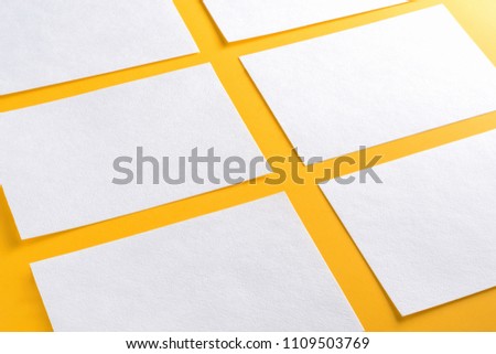 Mockup of horizontal business cards stacks arranged in rows at yellow background.