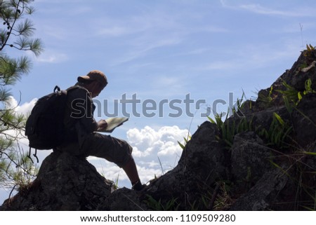 Male climber looking at the map and relaxing on the mountain. - Holiday activities. - Pictures with space for editing.