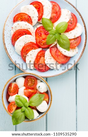 Tomatoes, mozzarella cheese, basil and spices on gray slate stone chalkboard. Italian traditional caprese salad ingredients. Mediterranean food.