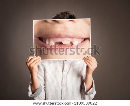little boy holding a picture of a mouth smiling