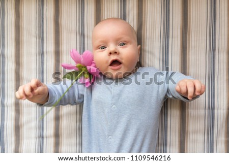 A small surprised child with large pink peony flower