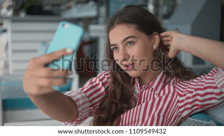 young brunette woman makes selfie indoors cafe