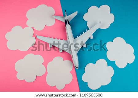 Model plane, airplane on color background. Paper clouds. Flat lay