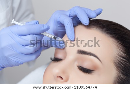 The doctor cosmetologist makes the Rejuvenating facial injections procedure for tightening and smoothing wrinkles on the face skin of a beautiful, young woman in a beauty salon.Cosmetology skin care. Royalty-Free Stock Photo #1109564774