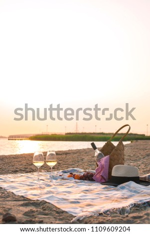Two glasses of wine and a basket for a picnic. Romantic on the beach and sunset. Vacation. Free space for text. Copy space