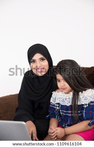 Arab woman teaching her daughter on laptop computer on white background