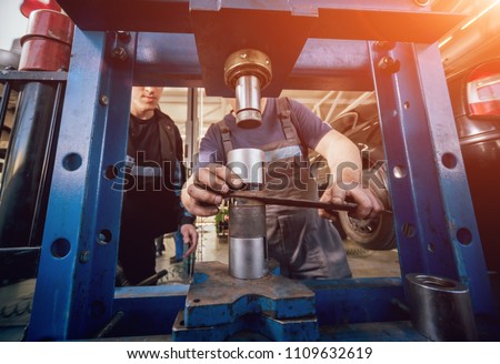 Car mechanic press new silentblock at repair service station. Auto service. Background Royalty-Free Stock Photo #1109632619