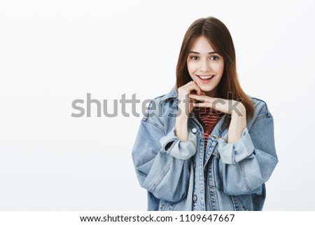 Charming girlfriend listening curiously interesting story. Portrait of pretty happy brunette in stylish denim jacket, holding hands above chin and smiling broadly, excited hearing amazing news