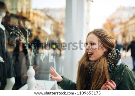 Attractive young long haired woman is excited in front of shopping window