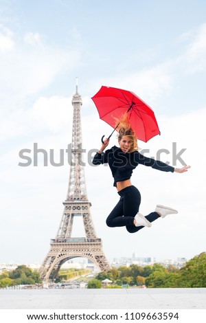 Lady with umbrella excited about visiting Eiffel Tower, sky background. Lady tourist sporty and active in Paris city center jumps up. Girl tourist enjoy walk and sightseeing. Dreams come true concept.