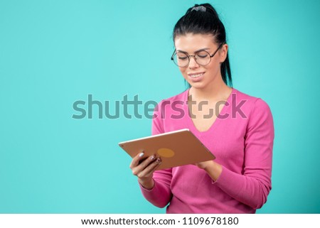 young beautiful woman learning to use tablet at work on the blue background. copyspace