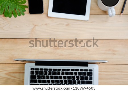 Workspace with laptop, tablet, smartphone and coffee cup on wooden desk.