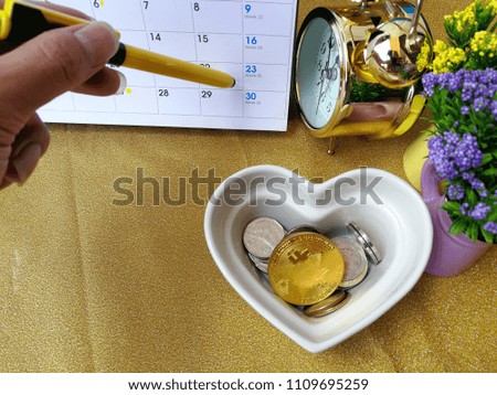 The hands are placed in a heart shaped tray with flower vases with a calendar and a gold clock with a colored pencil placed on the gold scene.