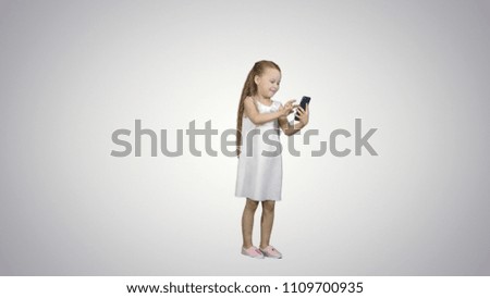 Cute little girl uses a smartphone and laugh on white background