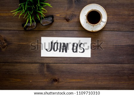 Template for socail media links. Hand lettering Join us on work desk with glasses, coffe, plant on dark wooden background top view copy space