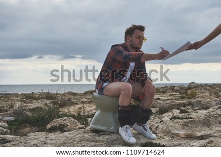 So busy. Funny guy is imagining that he is at the seashore while sitting on lavatory. He is signing document with seriousness. No time for vacation concept 