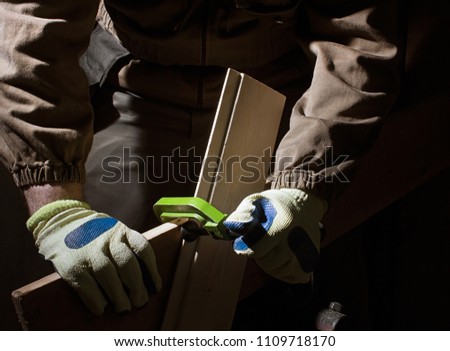 Photo of a worker in outfit with blue gloves working with metal clamp on black background with upper light and front view.
