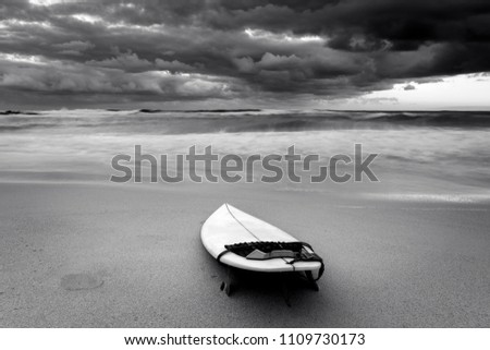 Black and white photo of a surfboard on the beach, Sydney Australia