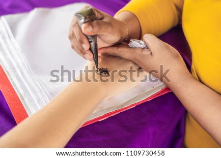 Woman is drawing on hand. Draw on the hand Indian mehendi picture.