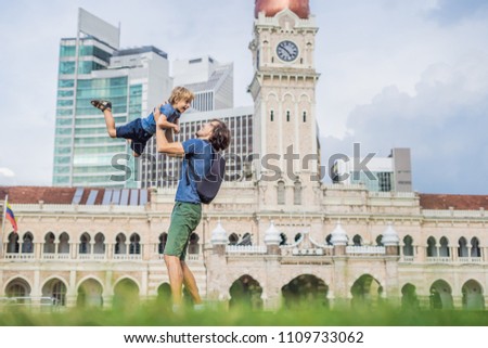 Dad and son on background of Merdeka square and Sultan Abdul Samad Building. Traveling with children concept.