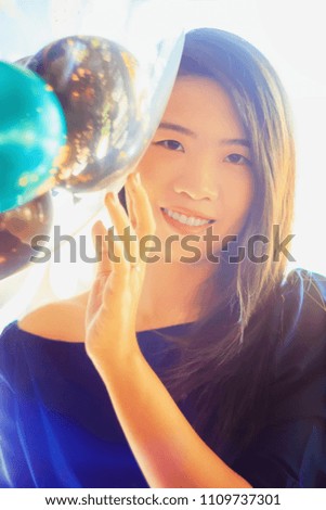 pretty Asian woman relaxing with balloon on light background, indoor portrait